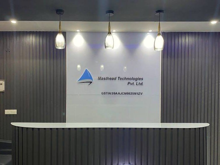 Reception identity on a white back panel set between charcoal fluted walls, the mark and lettering raised off the face so the pendant lights above throw a soft shadow behind them.