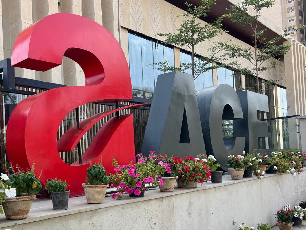 Oversized built-up brand letters and logo mark at a project entrance, finished in brand red and set against the building line.