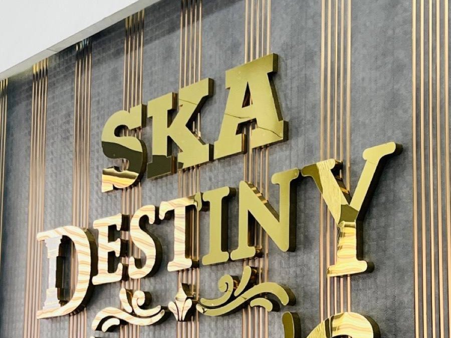 Ornate gold-finish built-up letters on a fluted stone elevation, the scrollwork cut to the same profile as the letterforms.