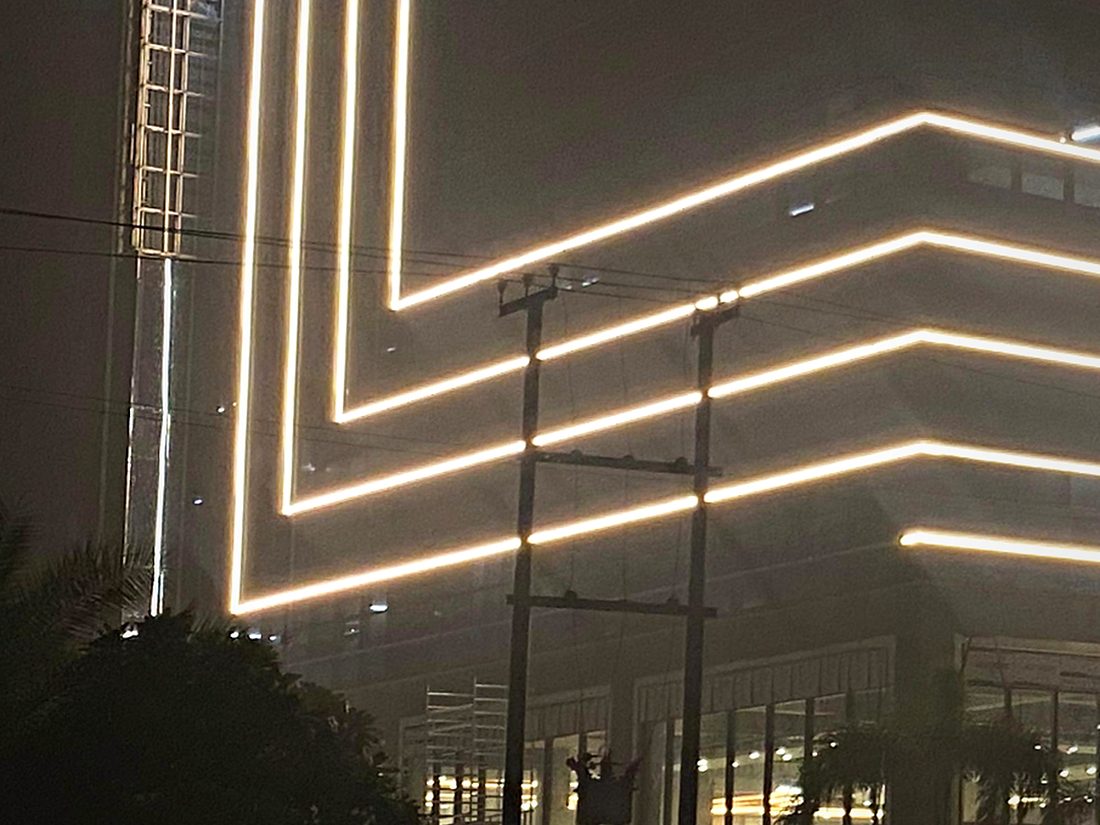 Continuous linear lighting following the stepped facade, turning the elevation itself into the night-time identity.