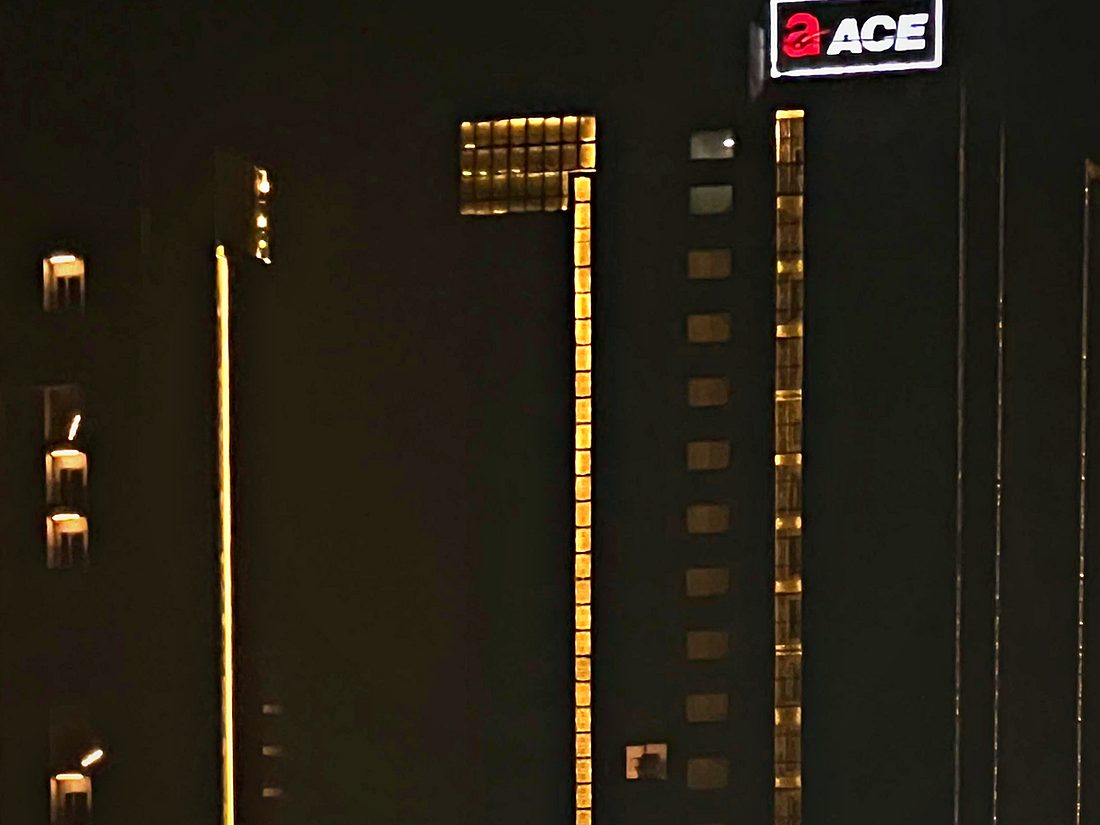 Vertical light runs carried up a tower elevation, aligned to the structural bays.