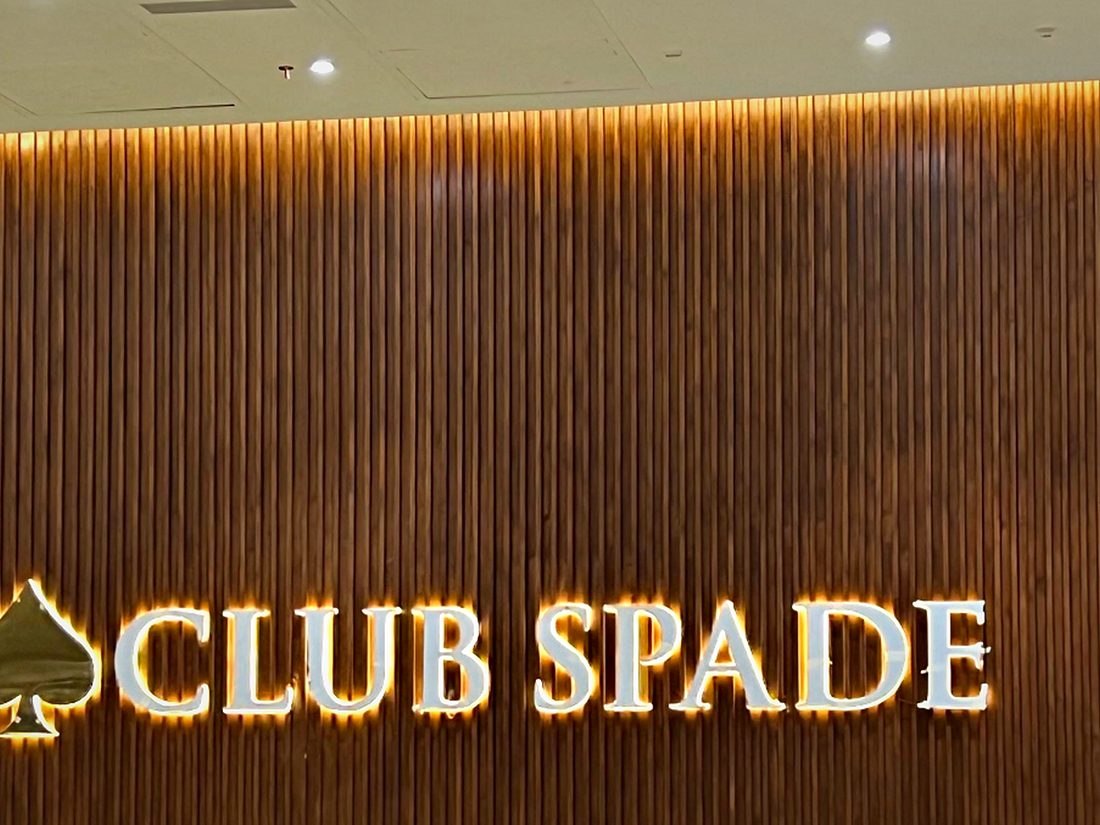 Halo-lit gold lettering and emblem on a fluted timber wall, set out on standoffs to give the glow room to spread.