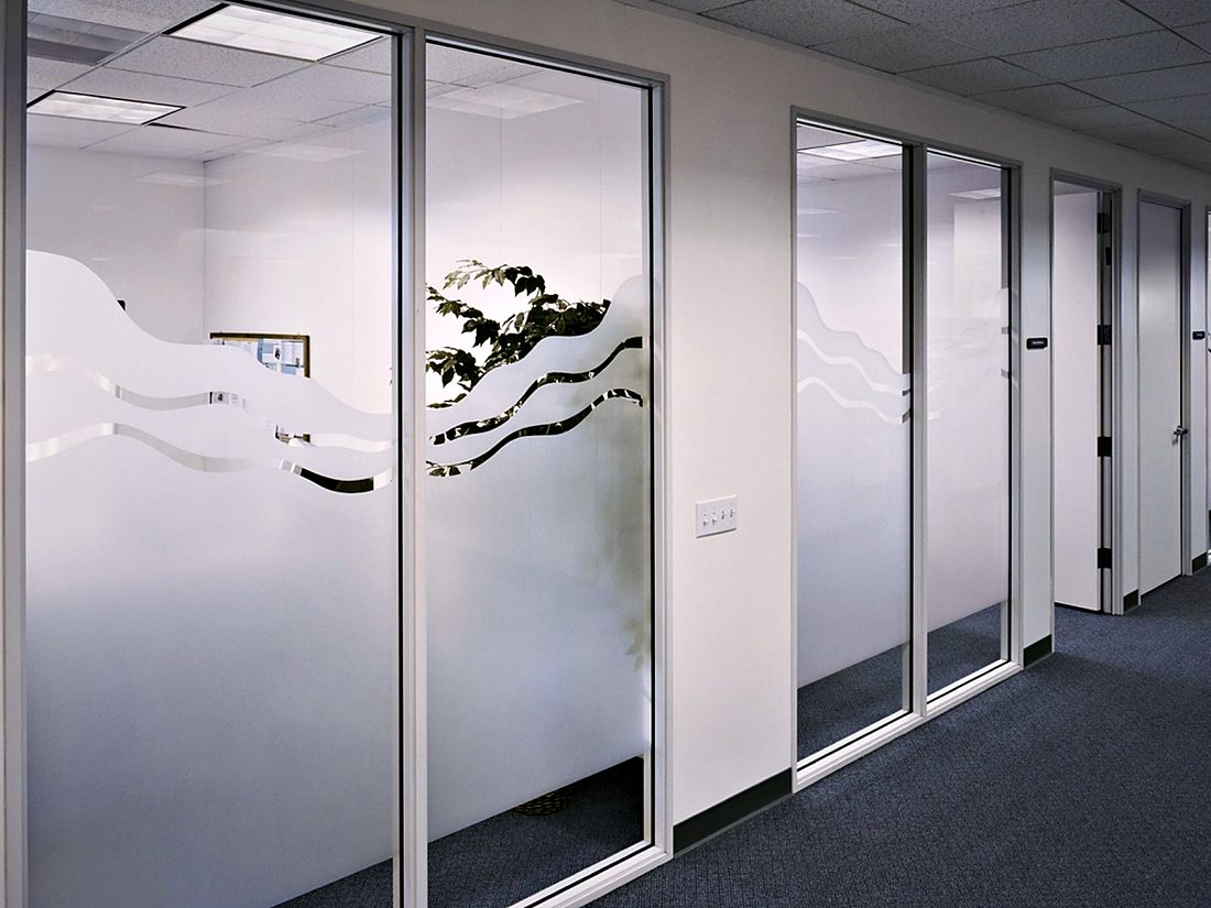 Organic leaf-pattern manifestation film on glazed office partitions — privacy and safety marking in one detail.
