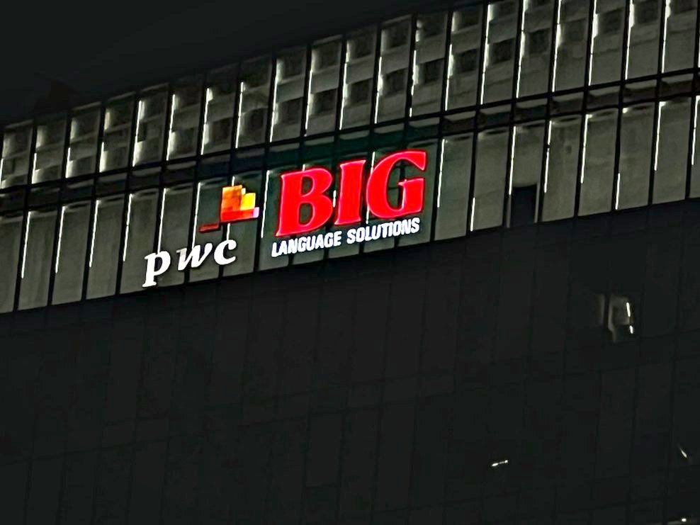 Illuminated office identity on a dark glazed elevation, using halo and face lighting together.