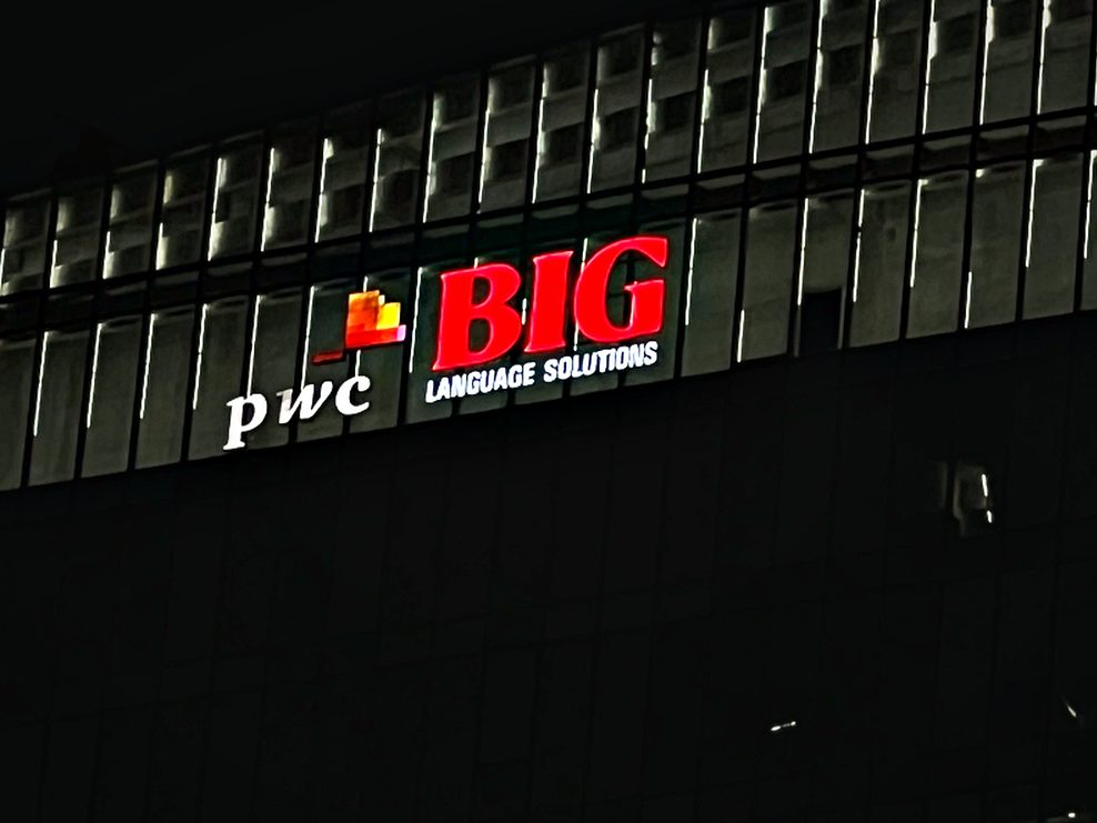 Illuminated office identity on a dark glazed elevation, using halo and face lighting together.