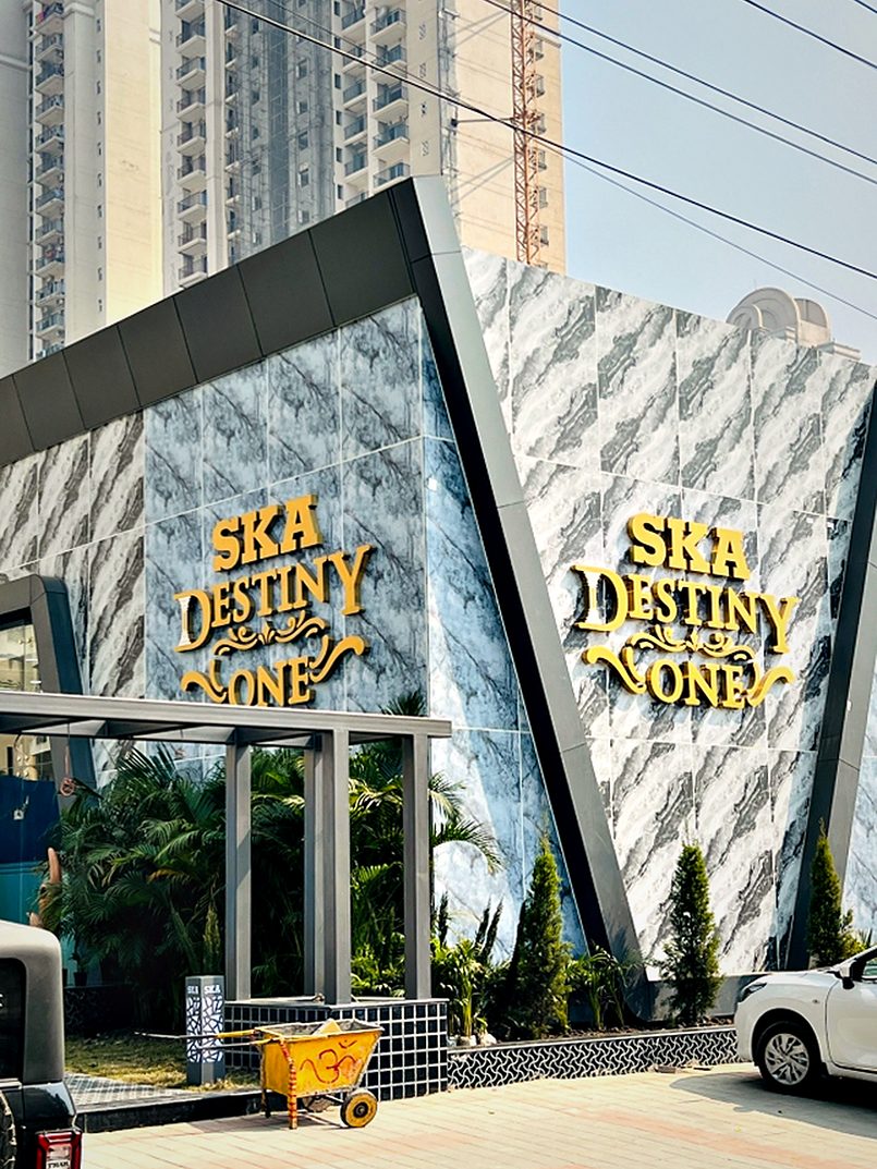Entrance monument in angled marble-pattern panels carrying dimensional gold lettering on both approach faces.