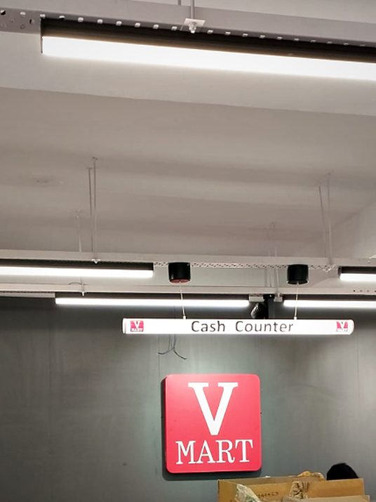 Illuminated counter identification inside a department store, hung to line through with the ceiling grid.