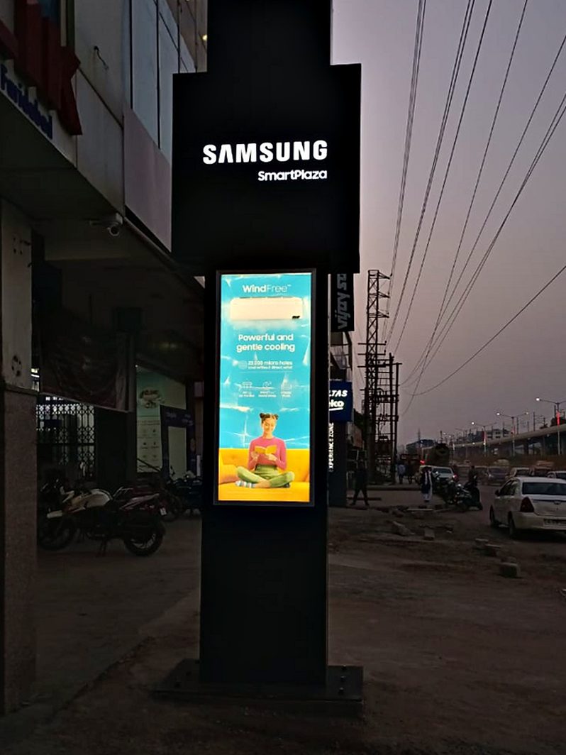 Freestanding roadside pylon carrying the store identity above a lit campaign panel.