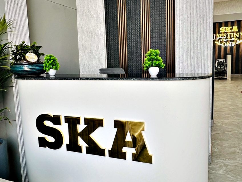 Mirror-finish metal lettering fixed to a curved solid-surface reception desk.