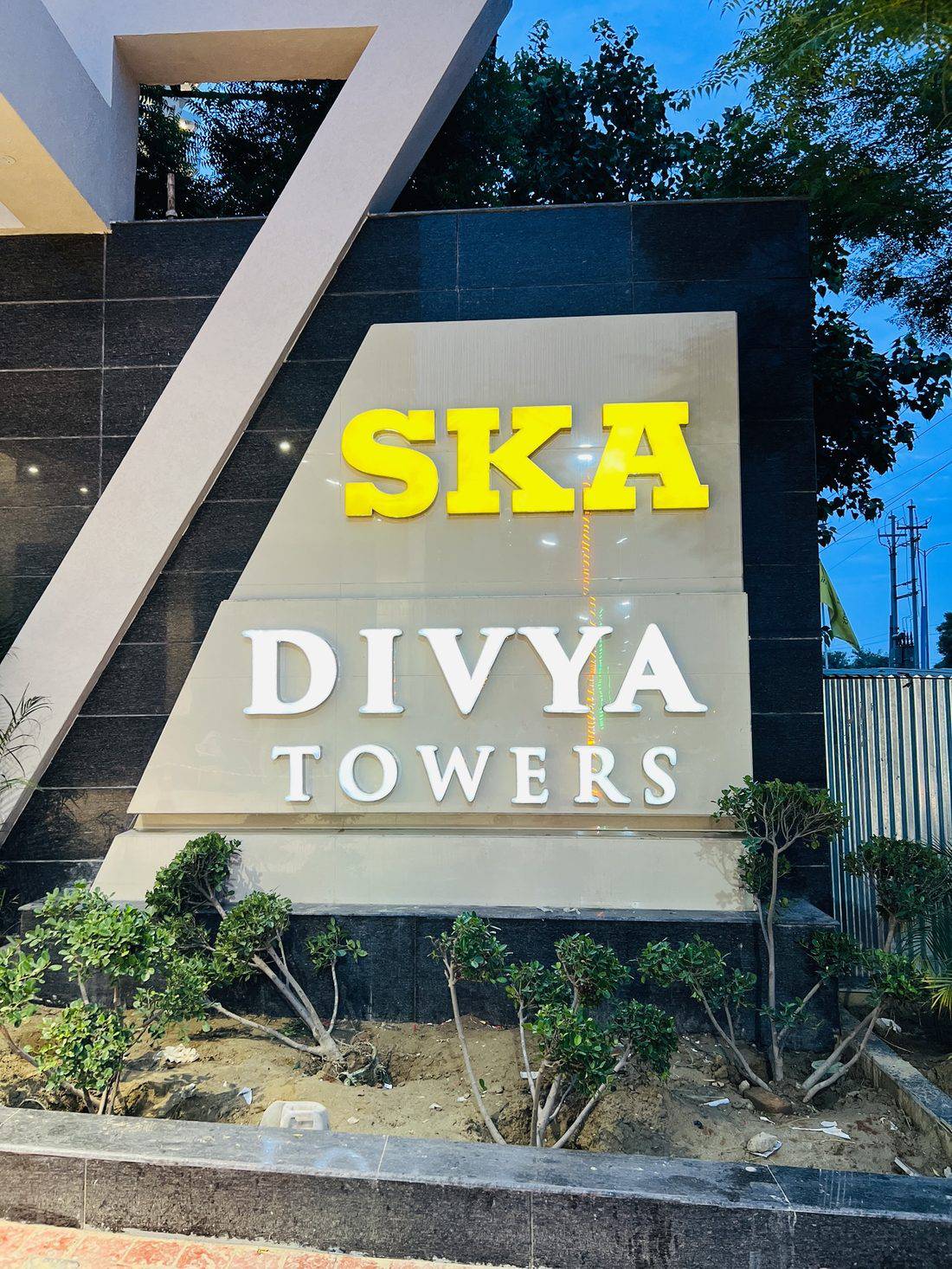 Monument entrance signage for SKA Divya Towers — dimensional gold lettering on a clad base that marks the project gateway.