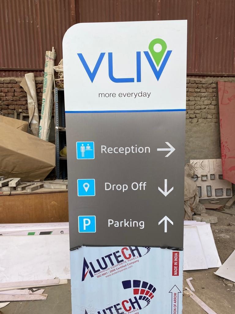Visitor wayfinding totem directing people to reception, drop-off and parking with clear icons and directional arrows.