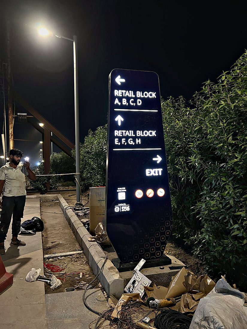 Night-lit directional totem that segments a township's retail clusters by block for quick, intuitive navigation.